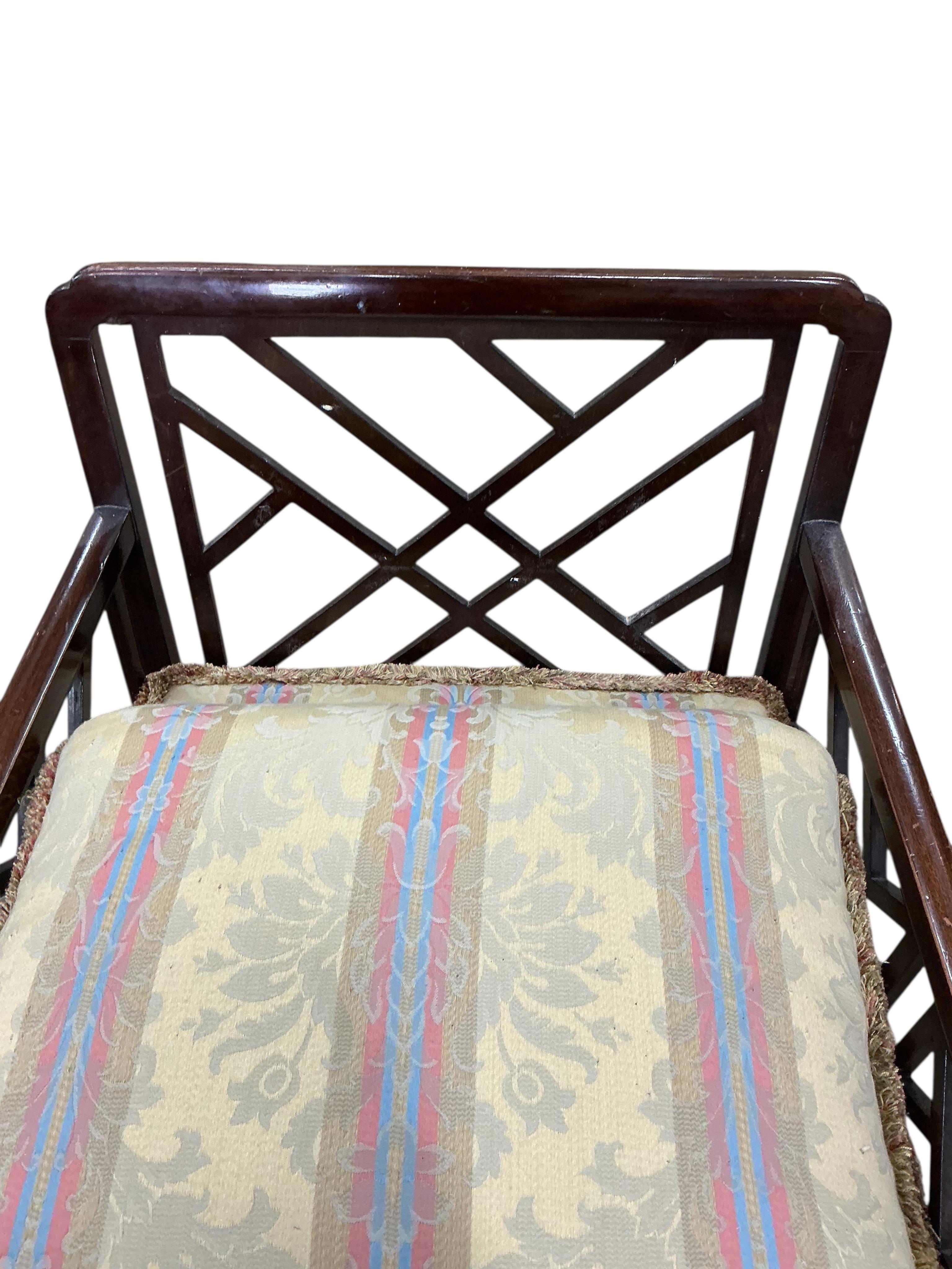 An early 20th century mahogany three piece suite comprising a sofa, width 134cm, depth 70cm, height 76cm and matching armchairs with fretwork sides